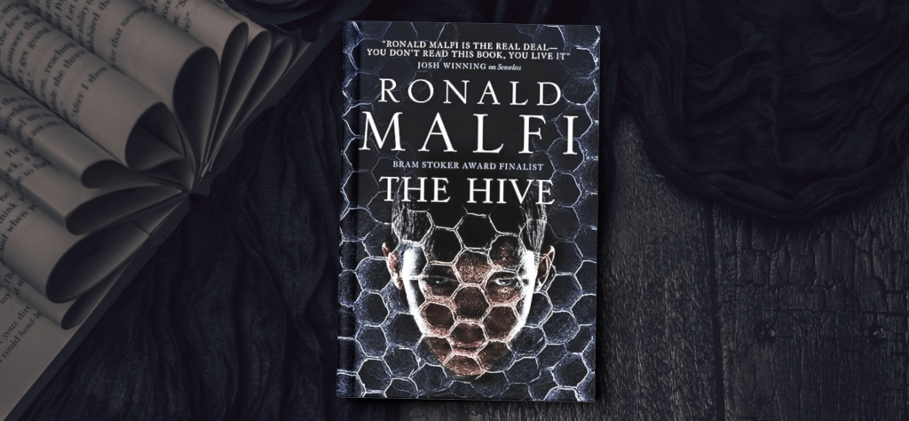 Book cover for The Hive by Ronald Malfi. A boy's face behind a silver honeycomb texture. The background features a deep blue cloth and and book with folded pages