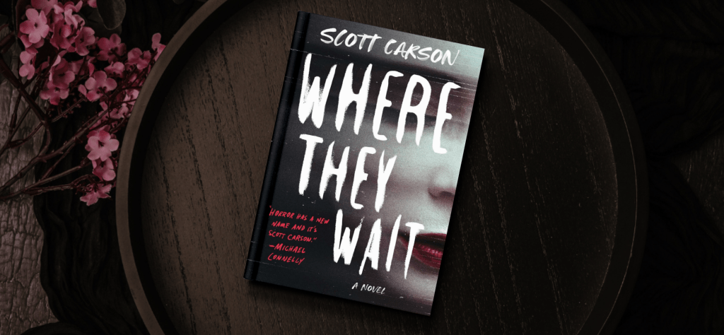 The book cover of Where They Wait by Scott Carson. The cover features a pale woman with dark, berry colored lipstick. The background features a wooden plate and pink flowers.